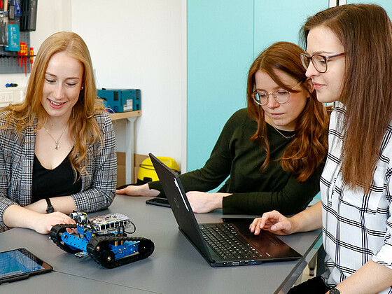 Academic staff programming a little robot with students